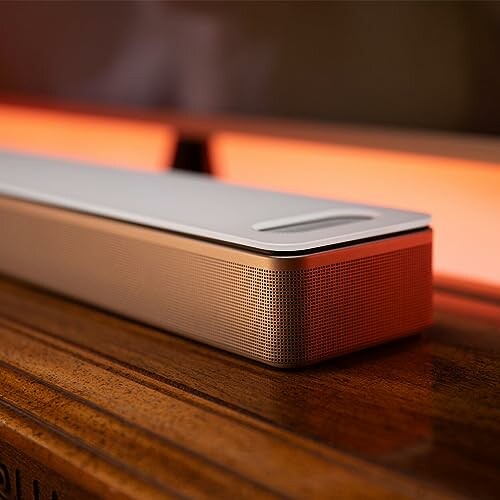 A sleek soundbar on a wooden surface with a warm light background.