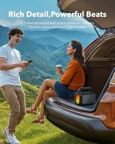 Two people enjoying music from a portable speaker on a car trunk in a scenic outdoor setting.