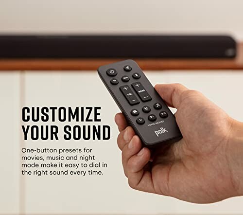 Hand holding Polk remote control for customizing sound.