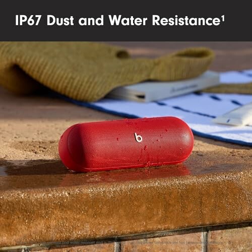 Red portable speaker with IP67 dust and water resistance on wet surface.