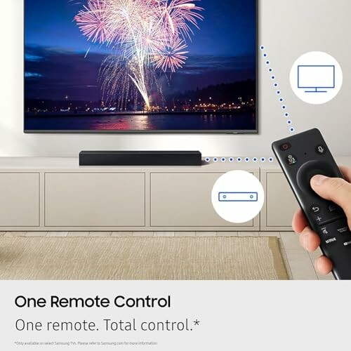 Hand holding remote control toward TV displaying fireworks.
